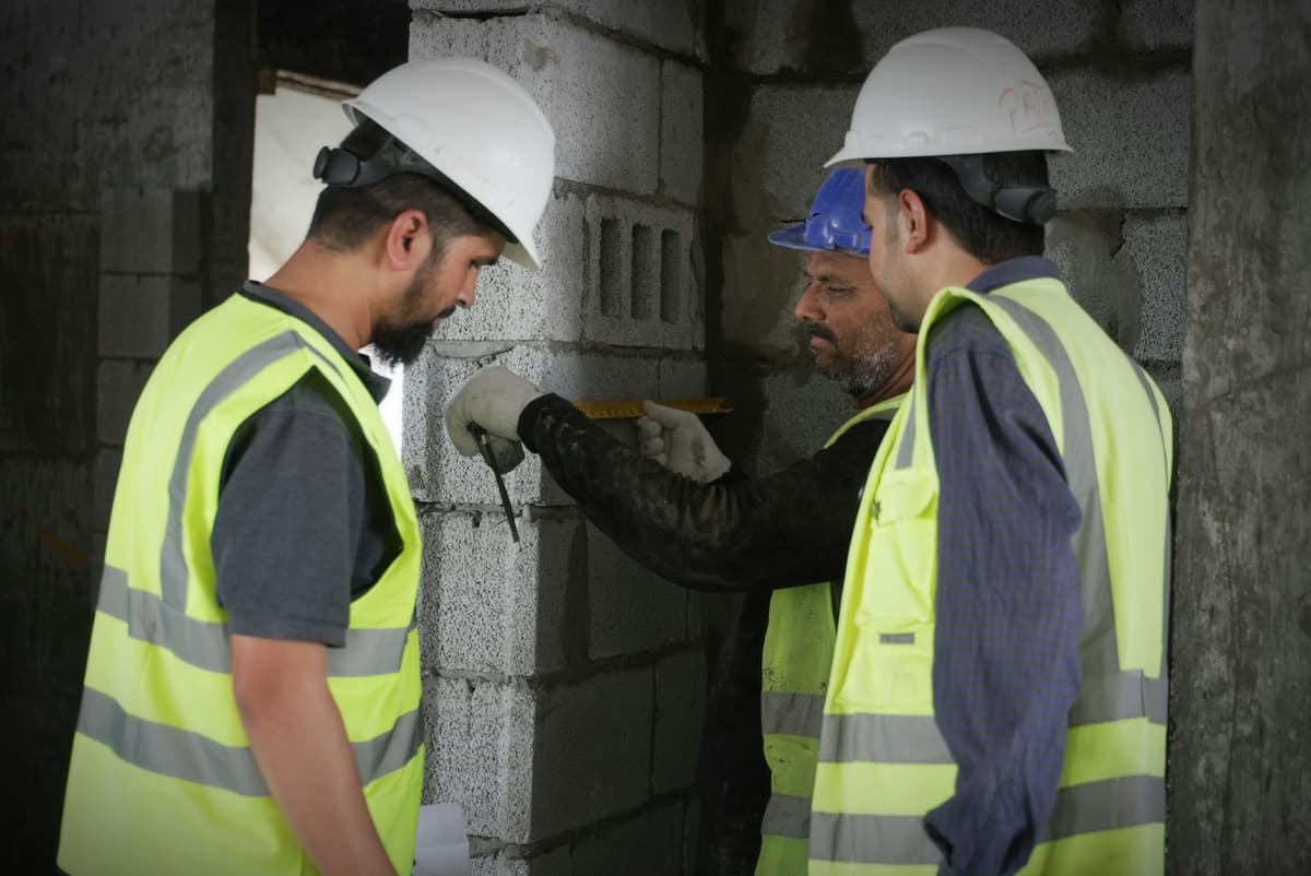 Ingénieurs mesurant un mur sur chantier